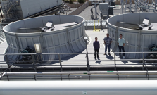 Three workers standing in front of two large turbines